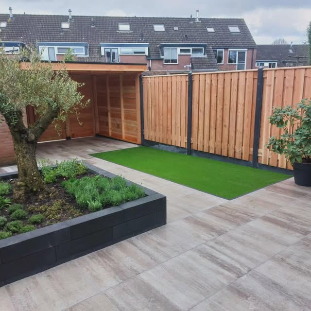 Aangelegde stadstuin met terras, groen en houten erfafscheiding