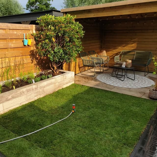 Aangelegde tuin met terras, gazon, beplanting en houten overkapping